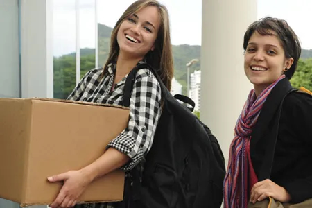 Two college students, one holding a cardboard box.