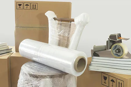 A pile of packing supplies and a chair covered in stretch wrap.